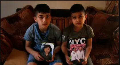 children hold pictures of their dead families that died in the sinking boat 
