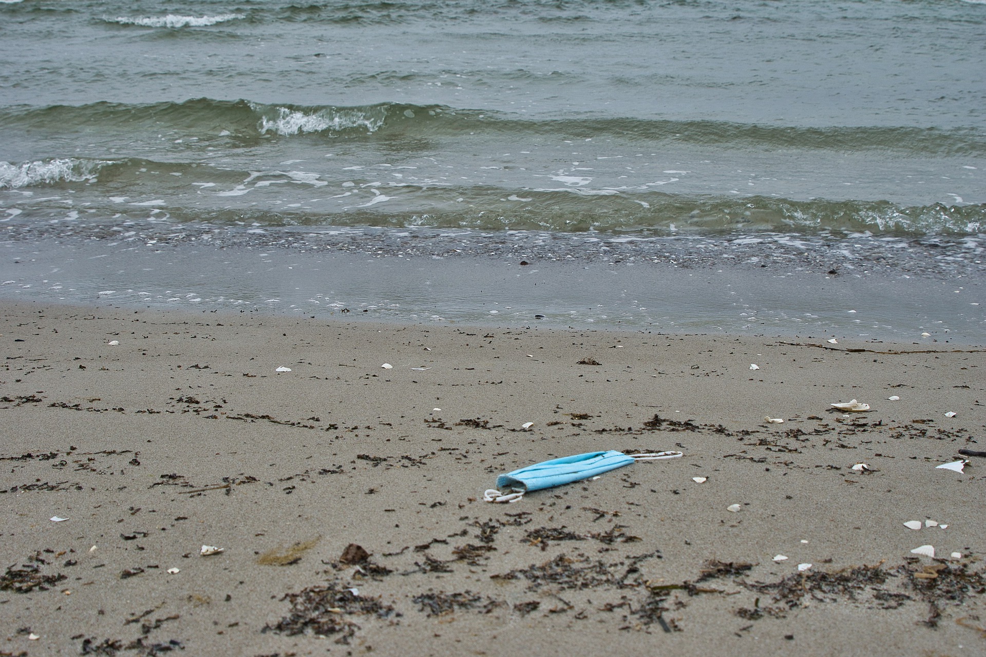 A facemask lying on the beach.