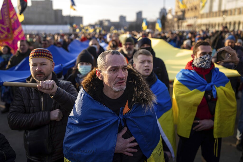 A demonstrator cries listening to a national anthem as other rallies with Ukrainian national flags in the centre of Kharkiv, Ukraine's second-largest city