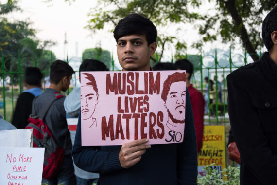 Man holding a banner that says Muslim Lives Matter.