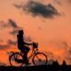 A man riding a bike and the sun is setting