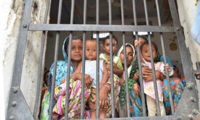 Children standing behind bars in a Jail.