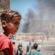 A child stands near a building in the port of Gaza that was damaged during an attack